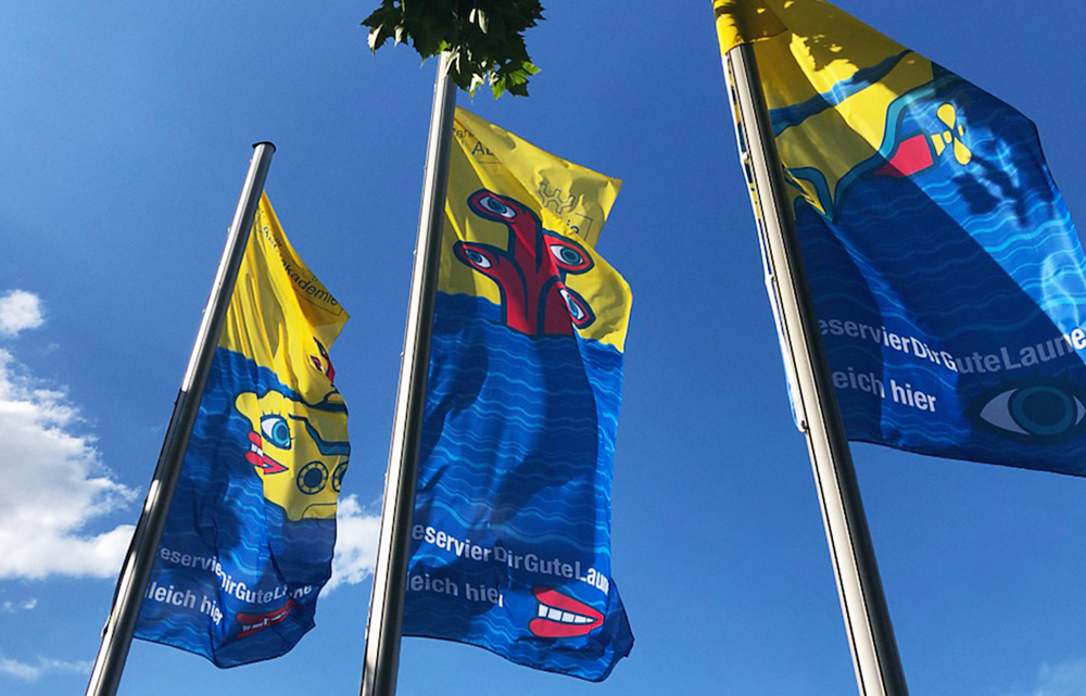 Gelb-rote U-Boot Teile wehen auf riesigen Hissflaggen im sonnigen Himmel über Mannheim